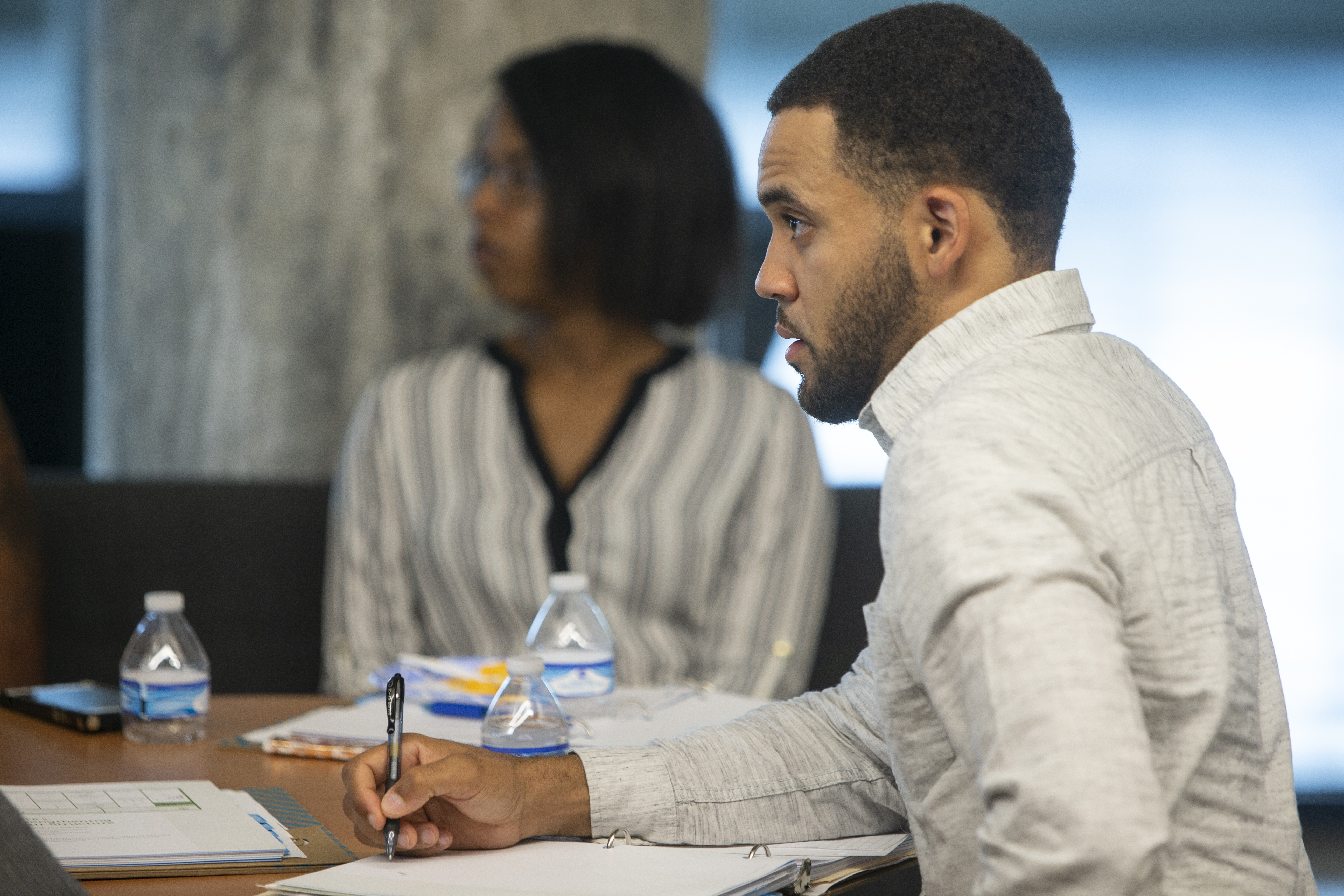 Professional taking notes during a meeting while listening to a colleague