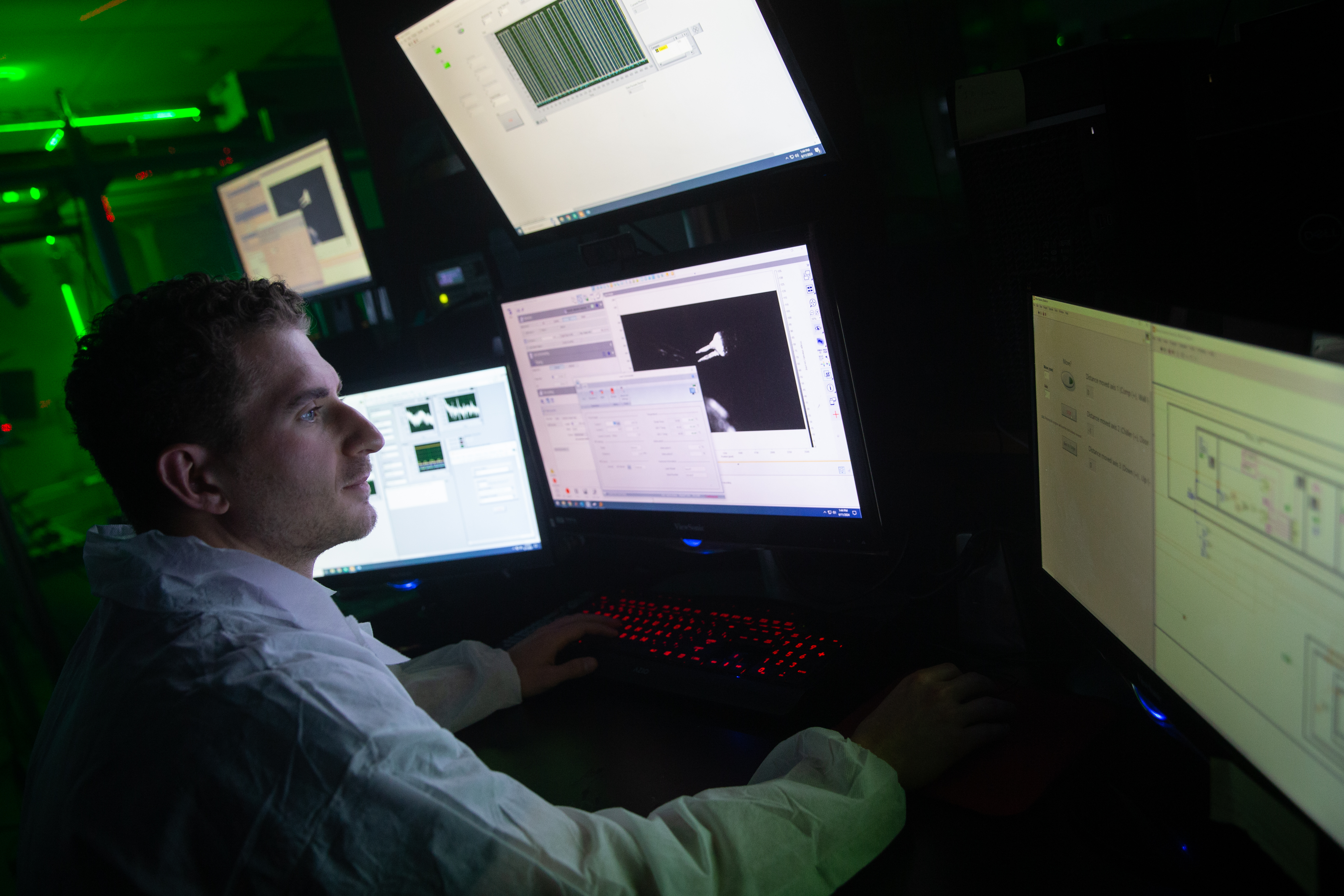 Person analyzing data on multiple computer screens in a lab setting