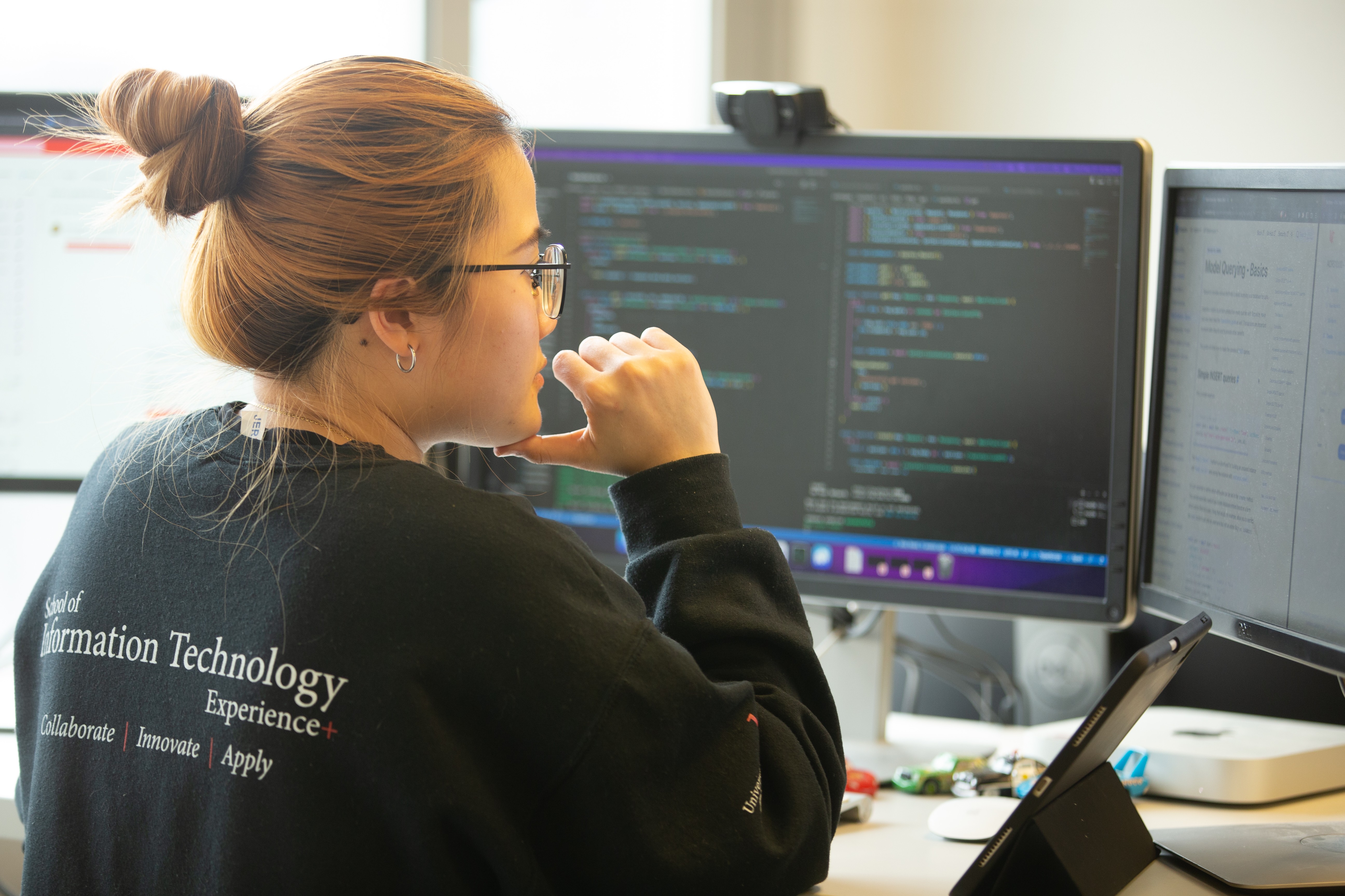Individual working on computer coding at a dual-monitor workstation