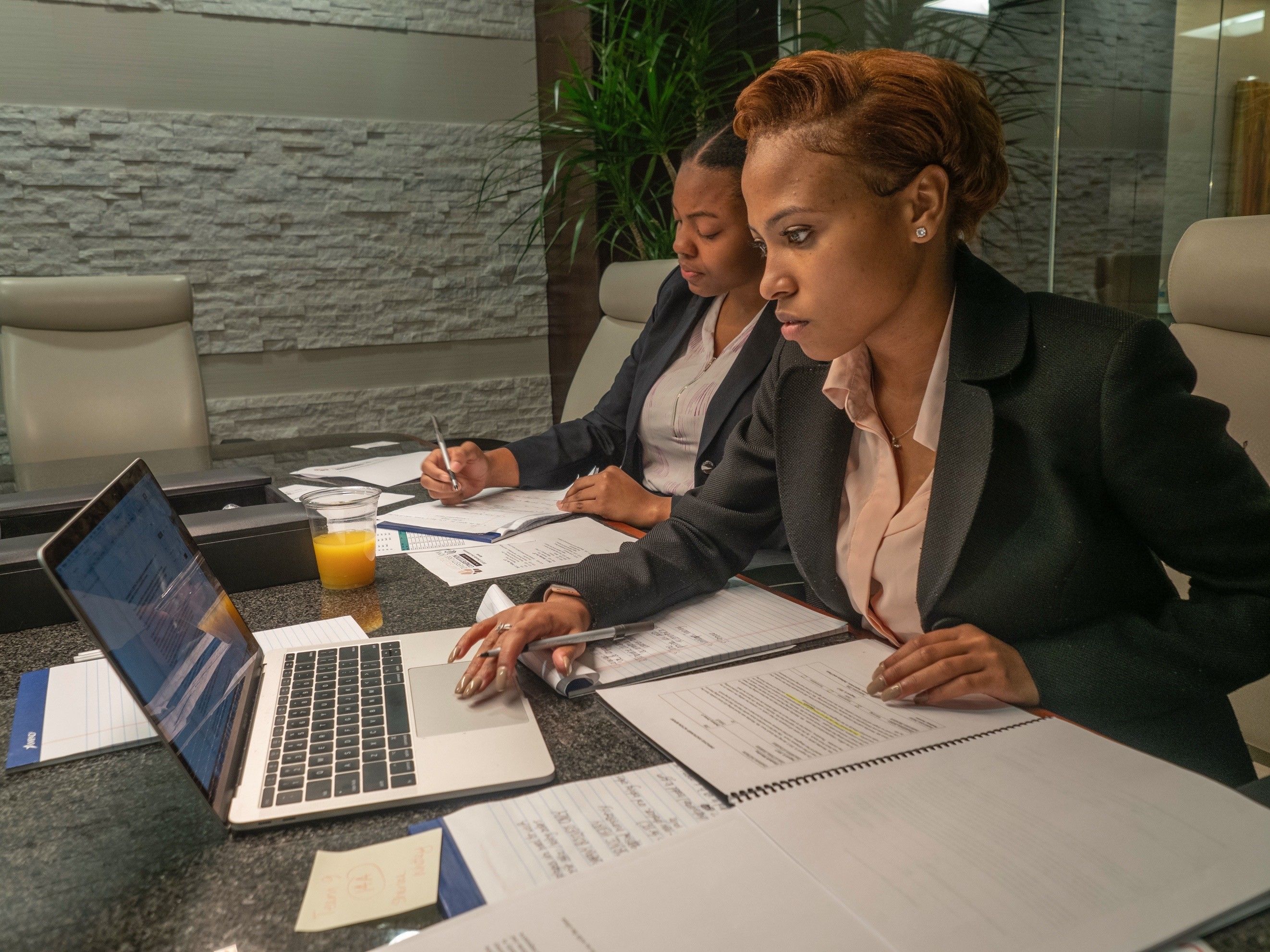 Two professionals working on a laptop with documents