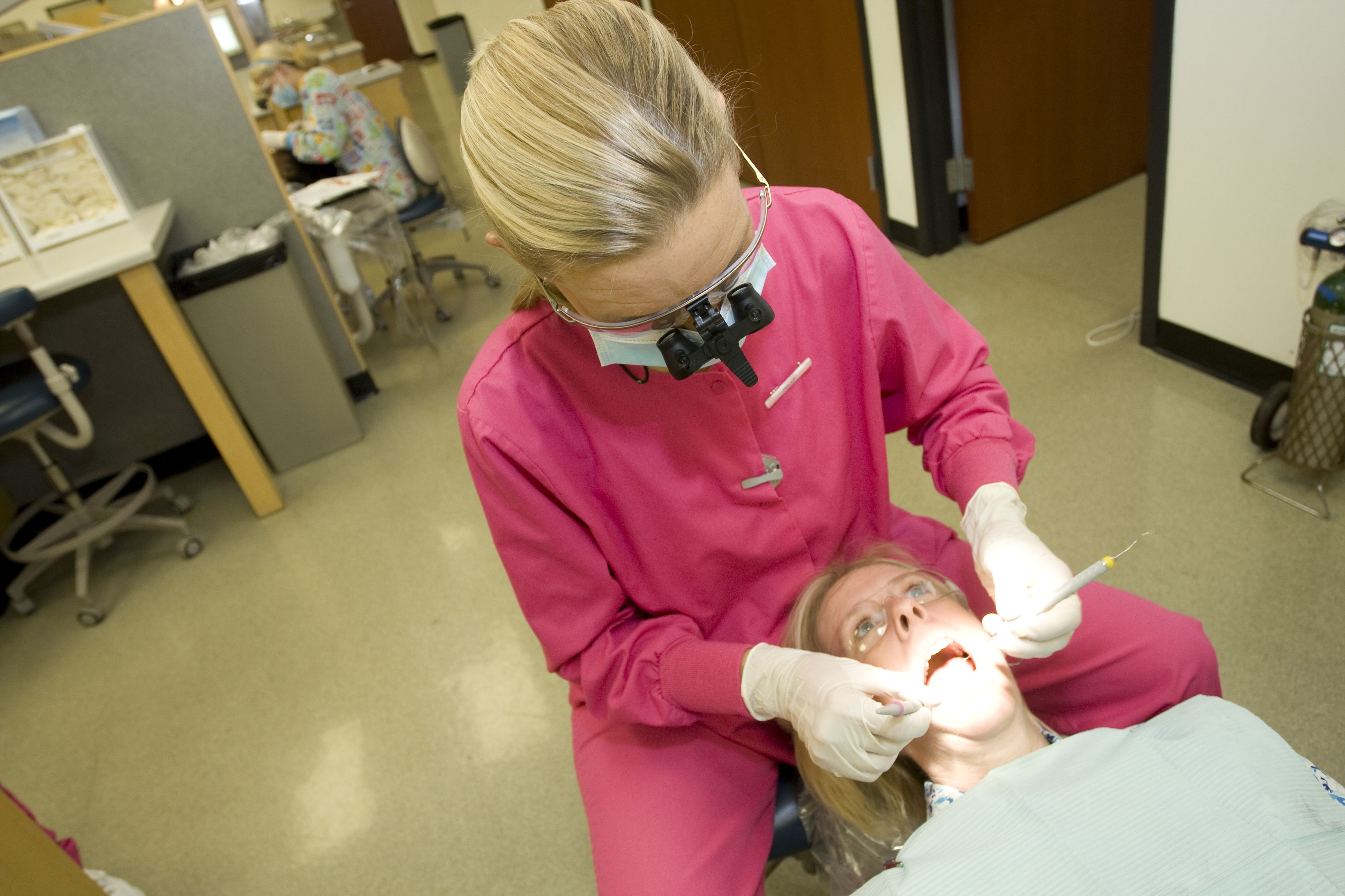 Dental professional performing a dental exam on a patient in a clinic
