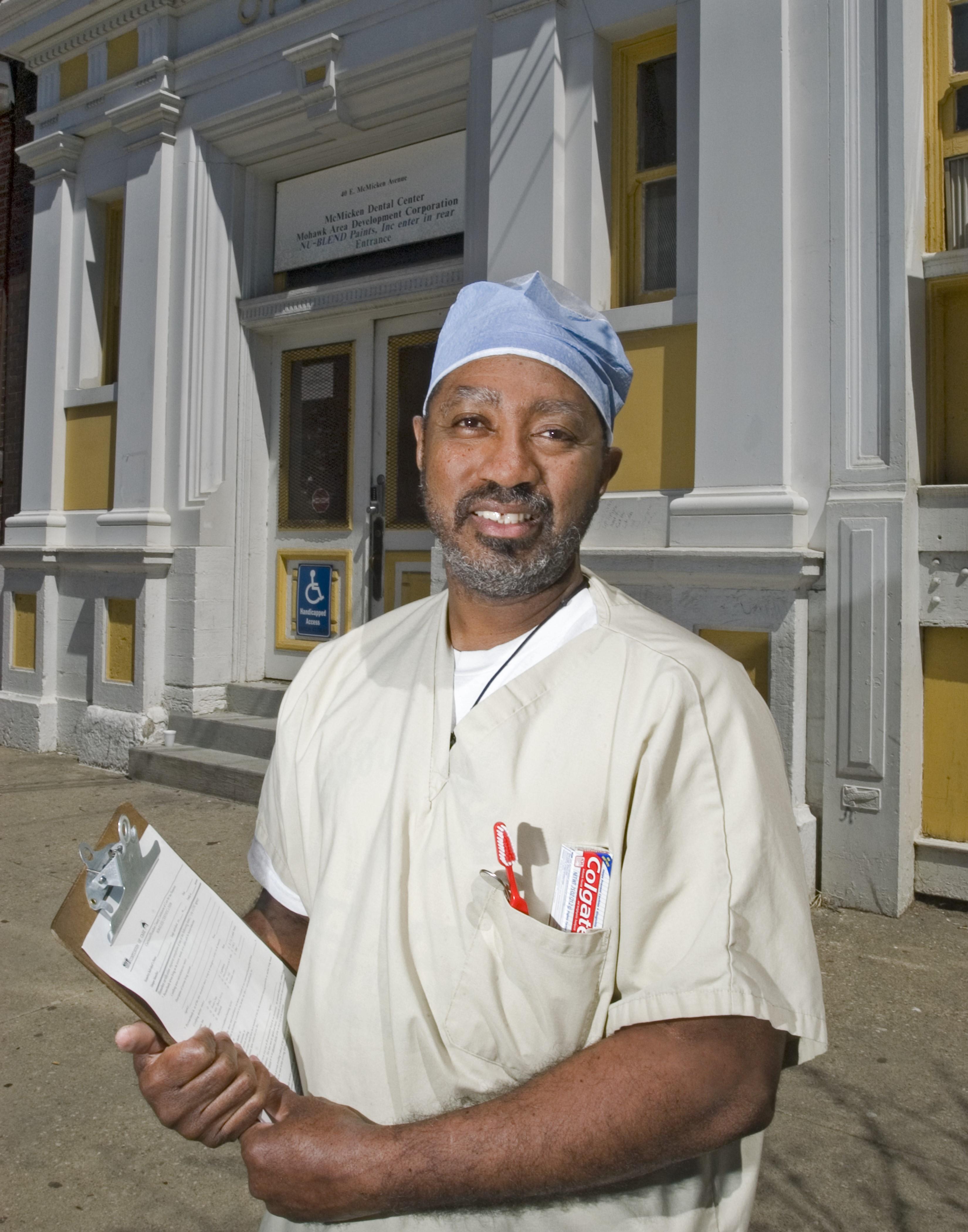 Healthcare professional in scrubs holding a clipboard outside a clinic building