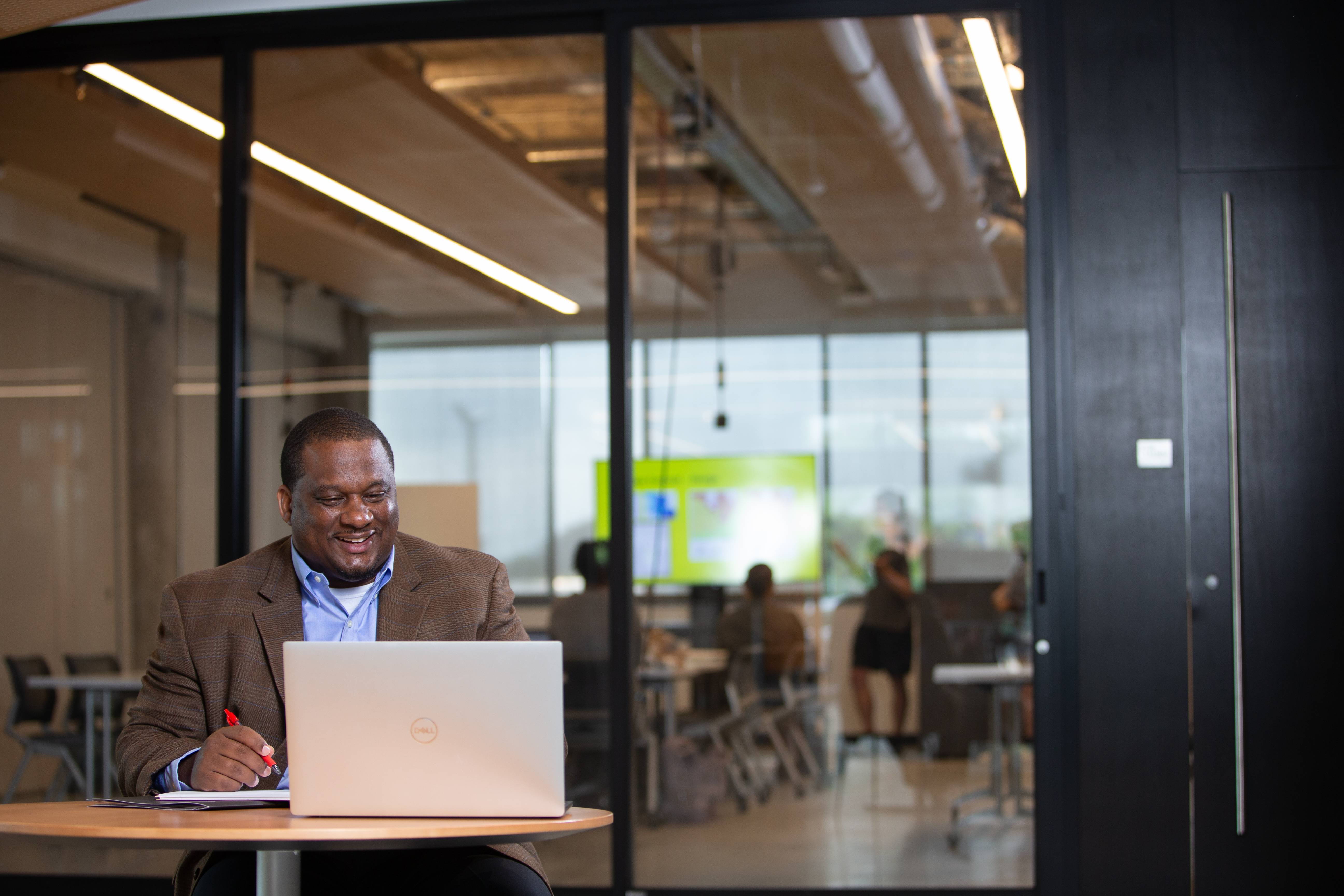 Person using a laptop and taking notes in a modern office