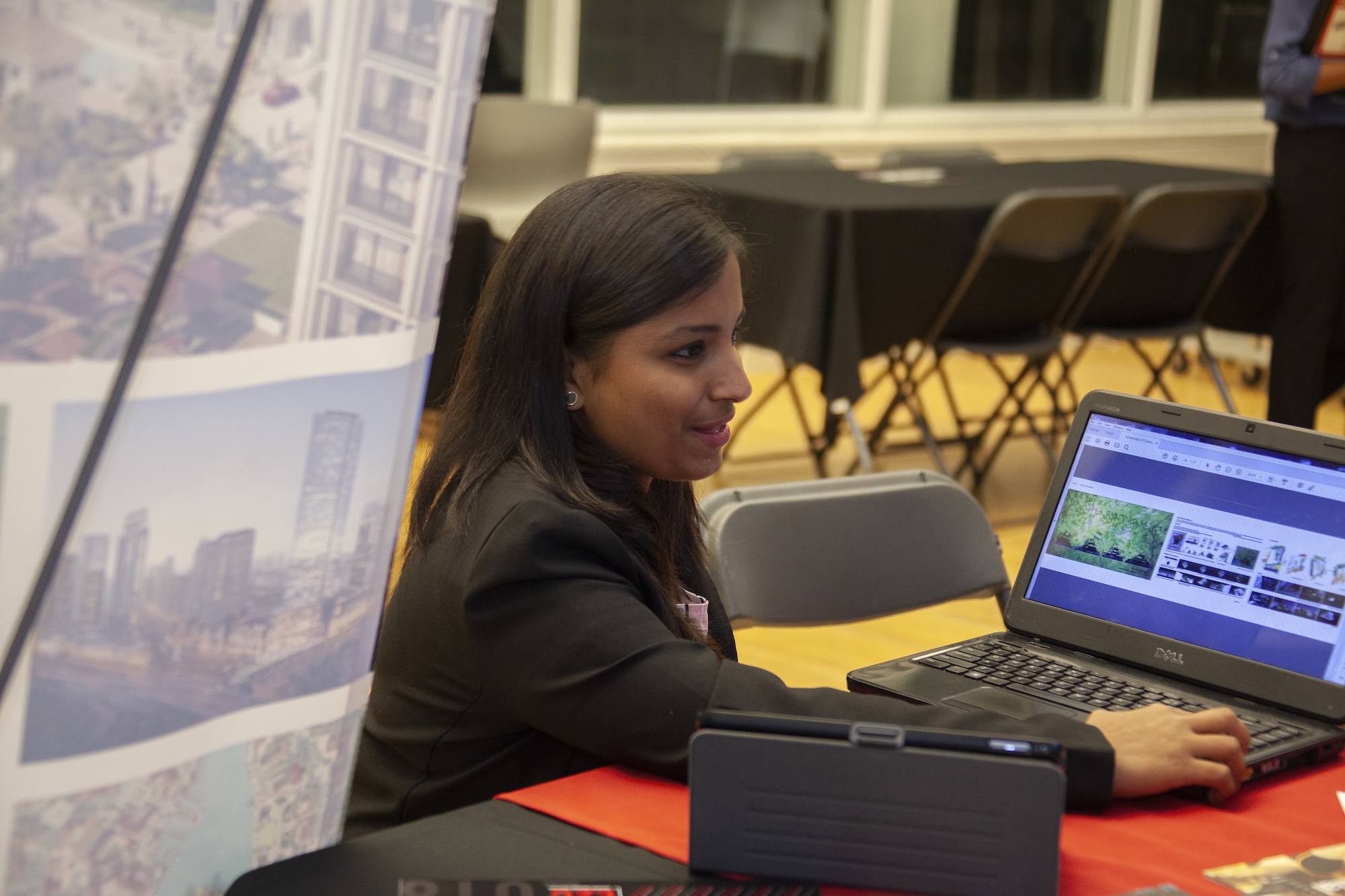 Professional working on a laptop with visual information displayed on the screen and a presentation board nearby