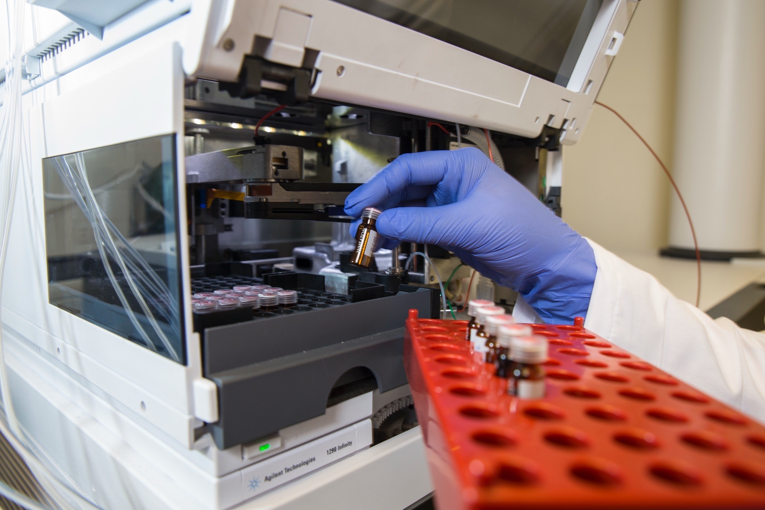 Laboratory technician placing a sample vial into scientific testing equipment
