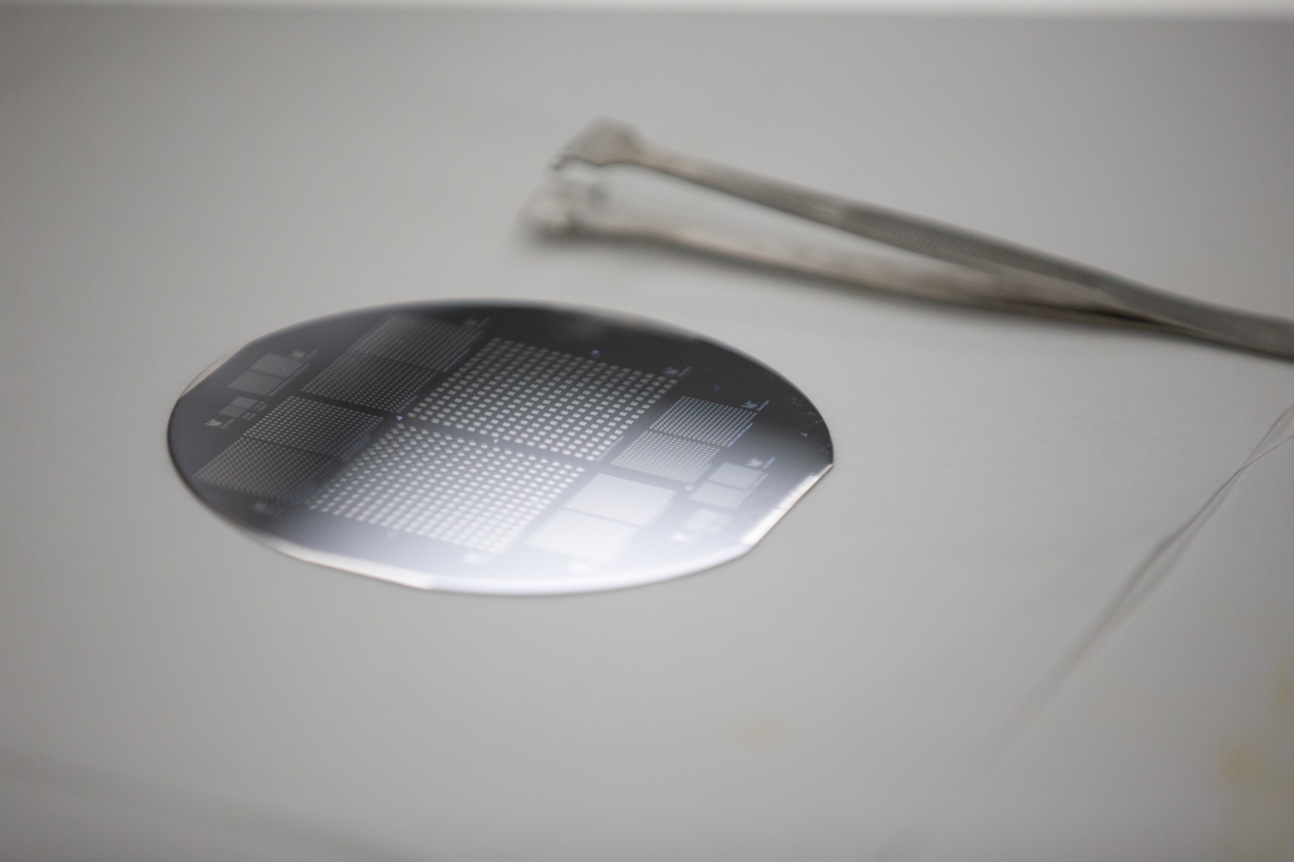 Semiconductor wafer with microchip patterns next to precision tweezers