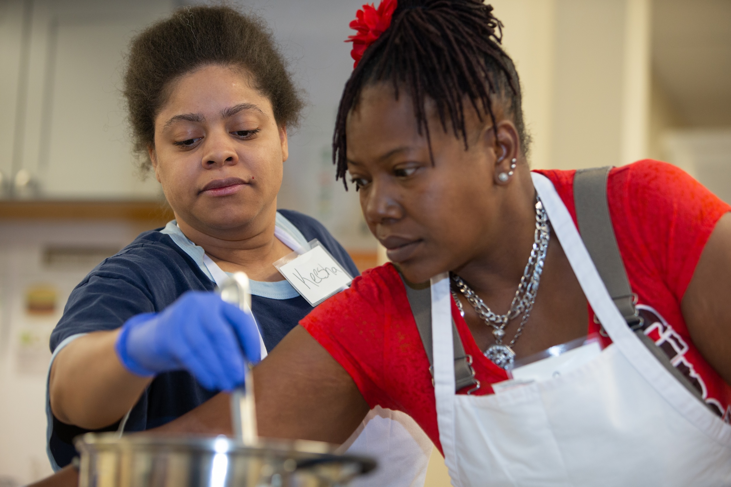 Two women participating in a hands-on cooking activity, preparing food together